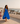 Woman wearing a blue Watamu linen halter dress on a Lamu rooftop overlooking the sea.
