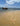 Footprints along a sandy Lamu beach with a dhow near the shore.
