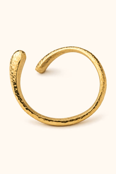 Nyoka Hammered brass bangle on a light background.