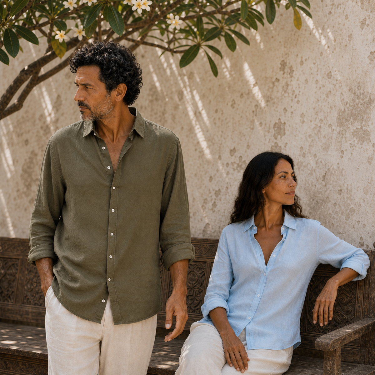 Man and woman wearing olive and pale blue Manda linen shirts in a courtyard.