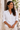 Model wearing hammered brass Machozi earrings and a white linen shirt.