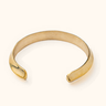 Wazi brass bangle on a light background.