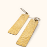 Kasai brass earrings on a light background.