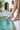 Woman wearing beaded leather sandals while sitting at the edge of a pool.