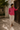 Man wearing a pink Manda linen shirt and light pants in a Lamu courtyard.