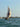 A dhow with a cream sail on blue water off Lamu.